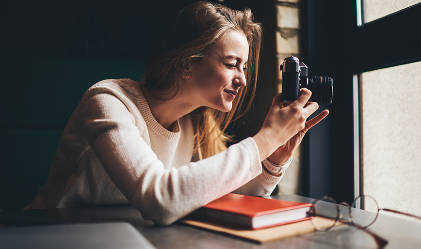 young-woman-taking-photo-on-camera-sitting-at-tabl-QZYKHKP